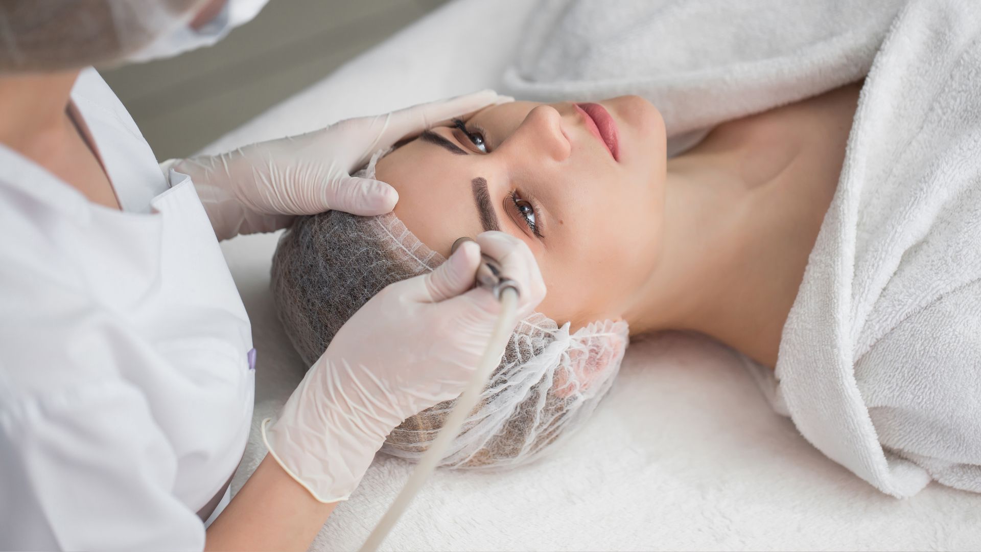 A woman getting a facial peel from a doctor